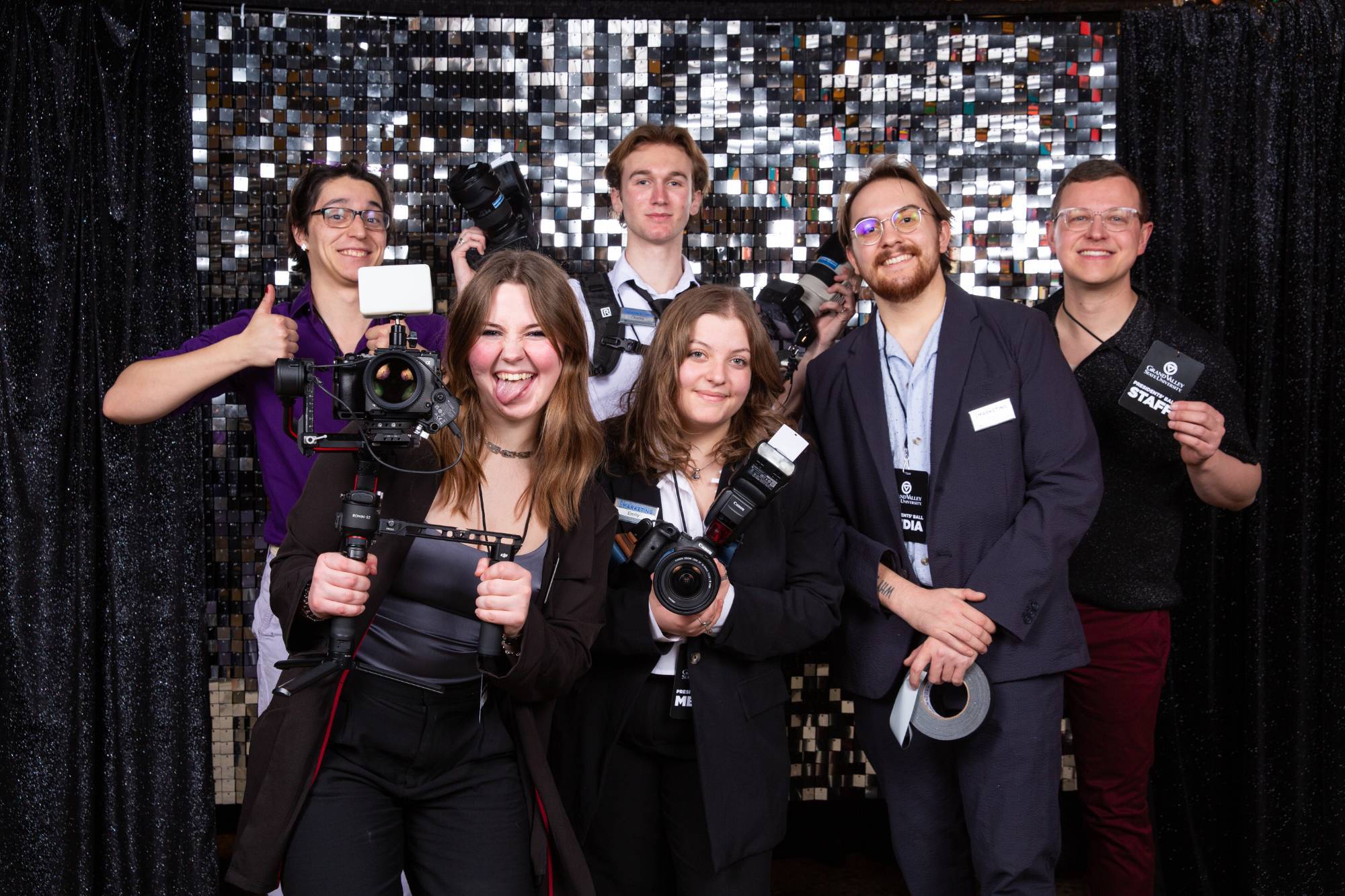 a group of photographers and GV Promotions Office staff members pose in front of a backdrop